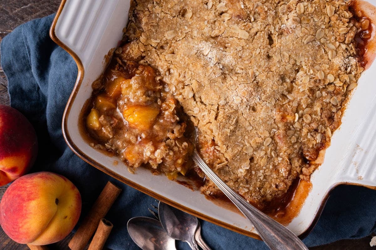 baked peach crisp in a white baking dish