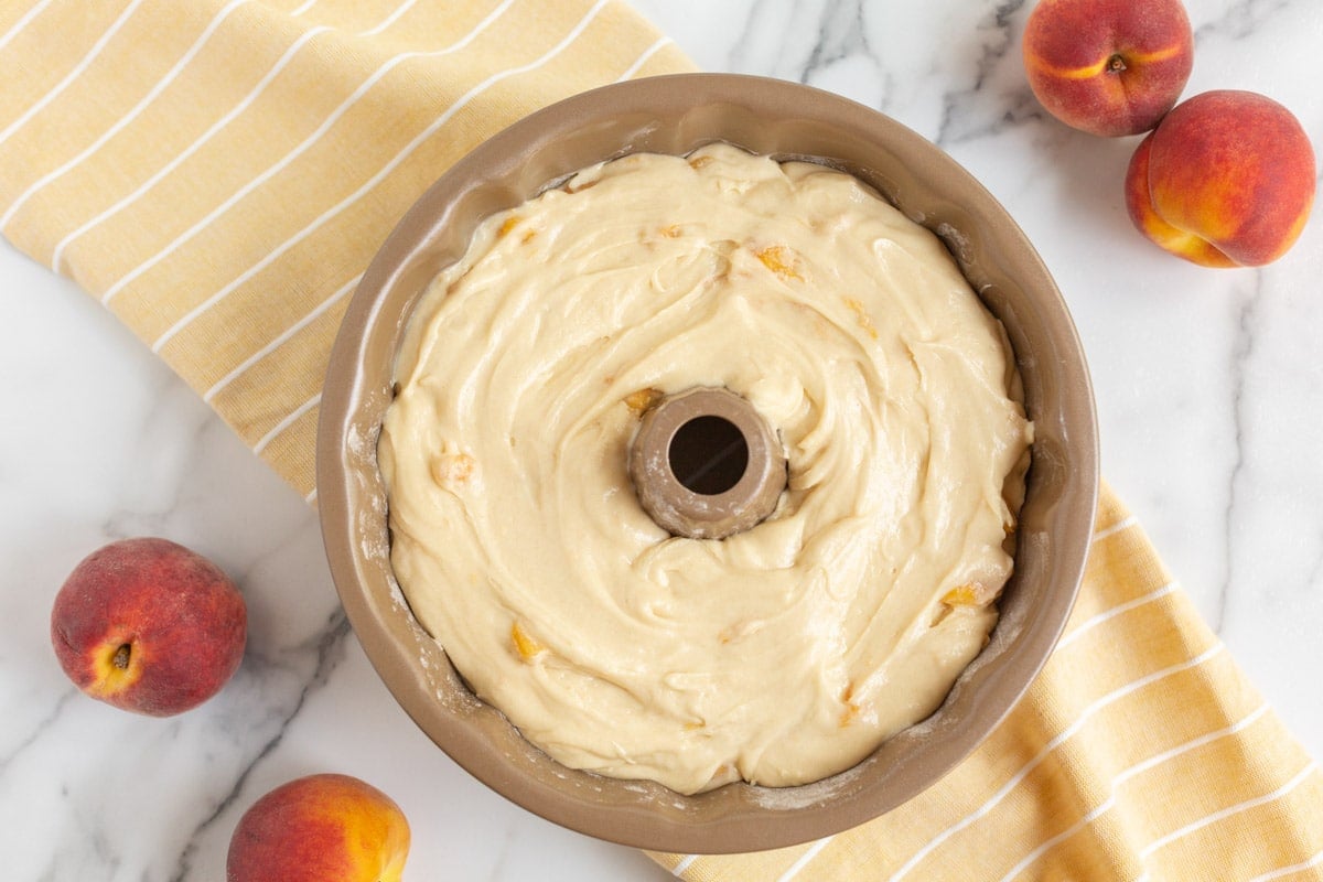 unbaked pound cake with peaches on a table