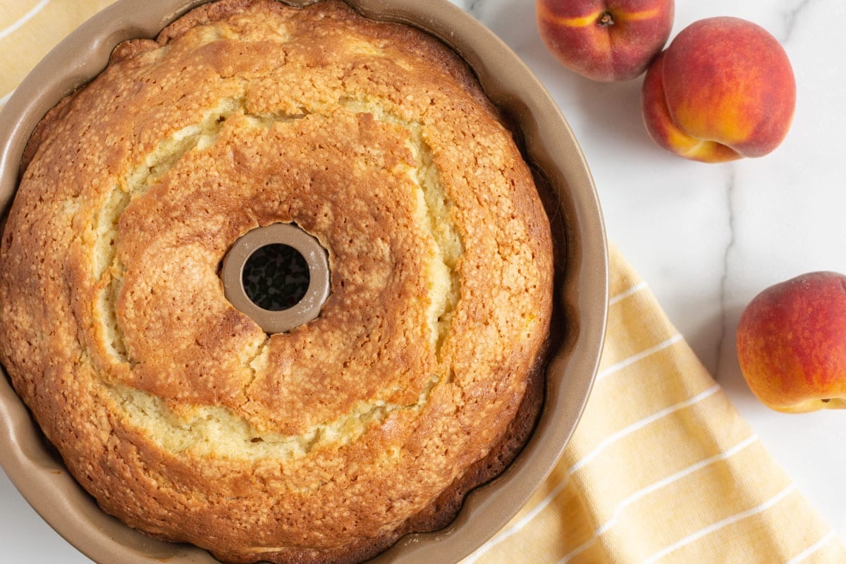 a bundt cake on a table with peaches