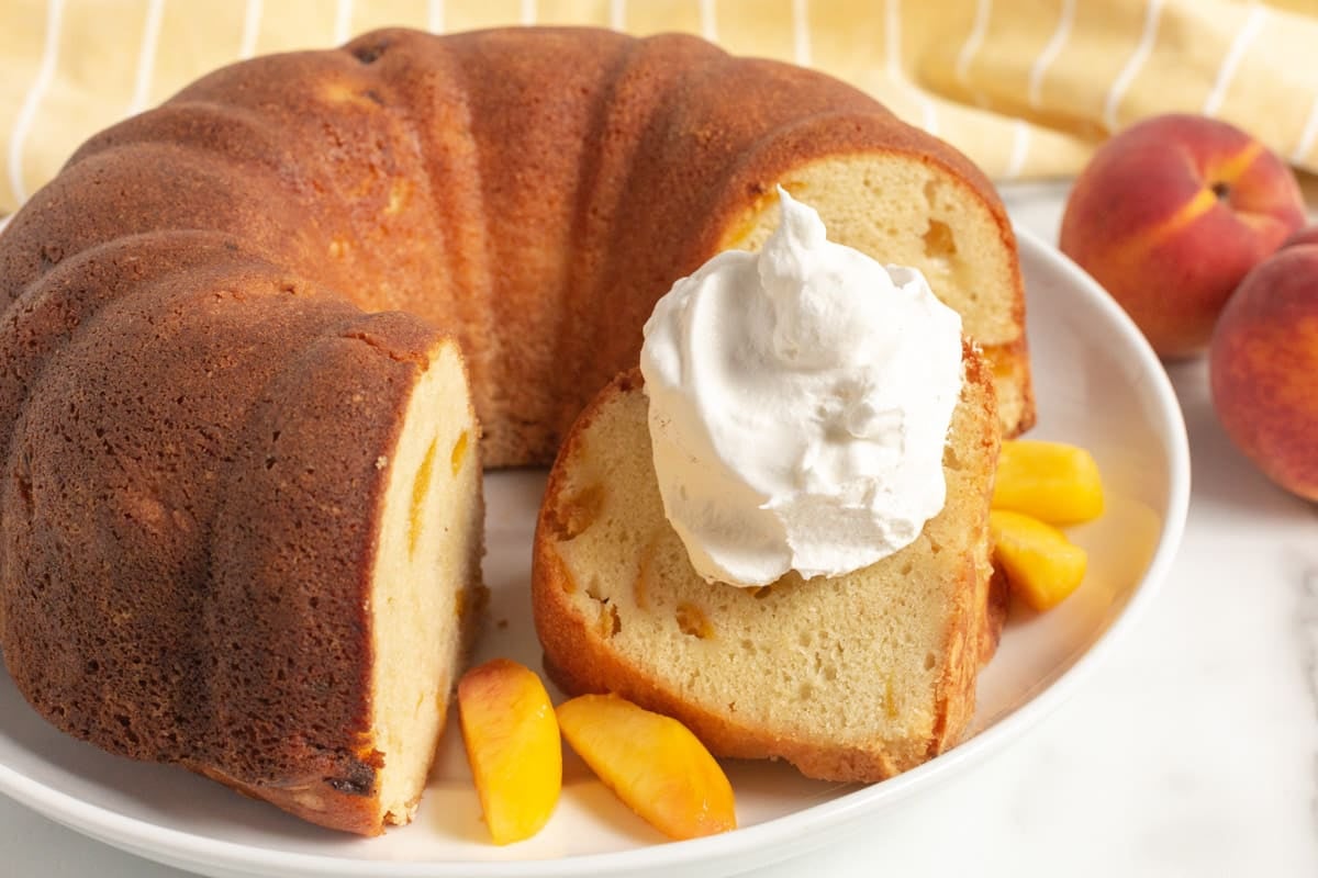 peach cake on a plate with peach slices and whipped cream