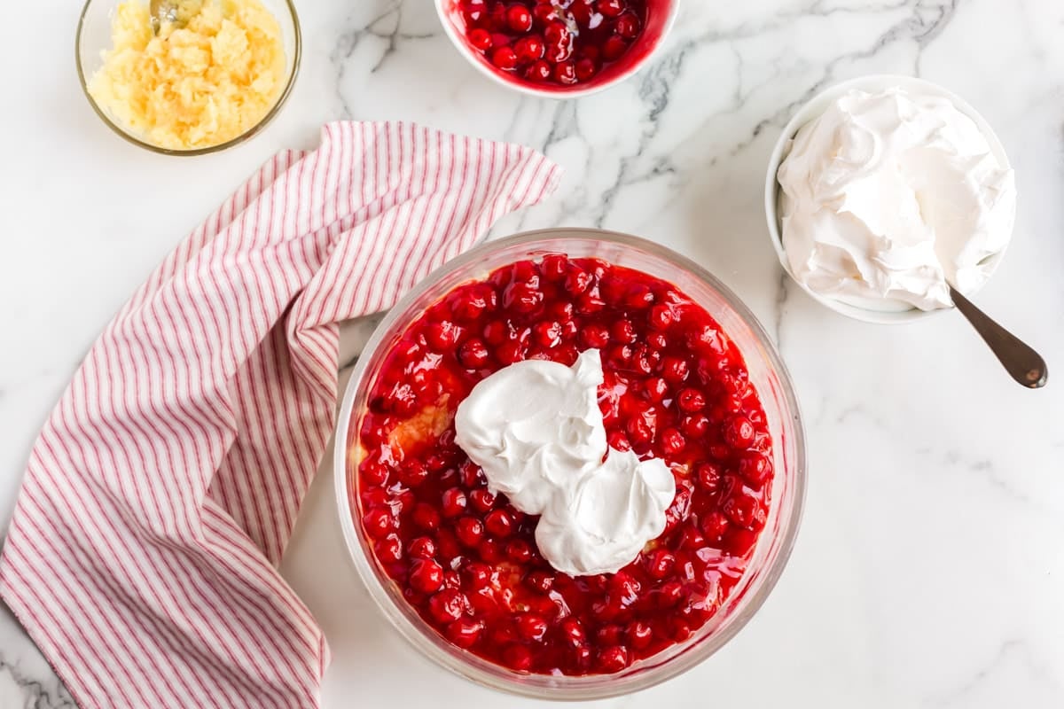 whipped cream over cherry pie filling in a glass bowl