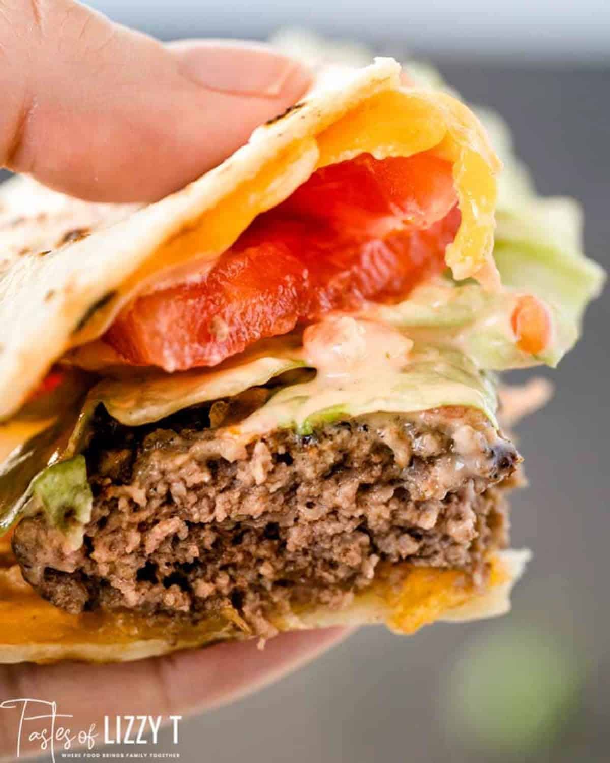 a hand holding a quesadilla burger