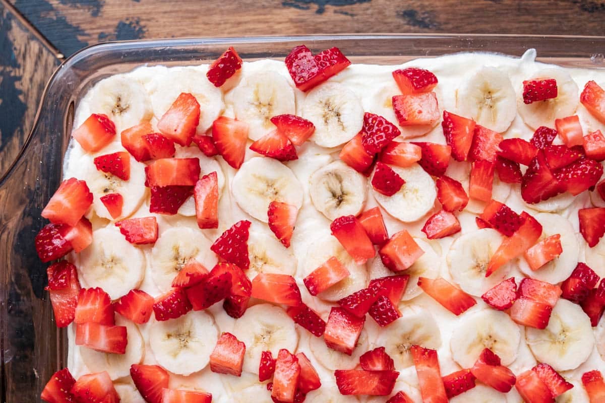 strawberries and bananas on top of an icebox cake