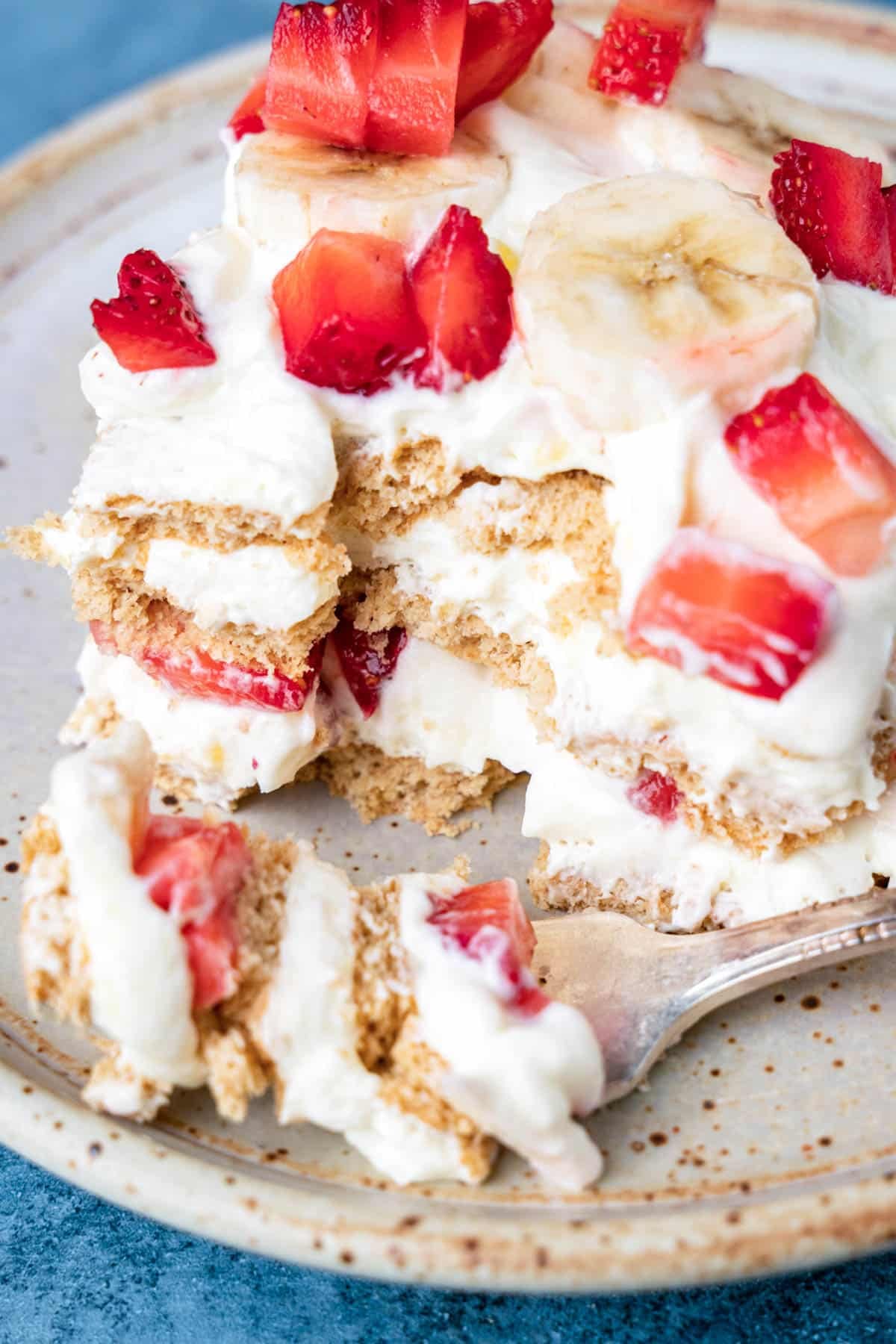 a piece of strawberry icebox cake on a plate with a bite on a fork