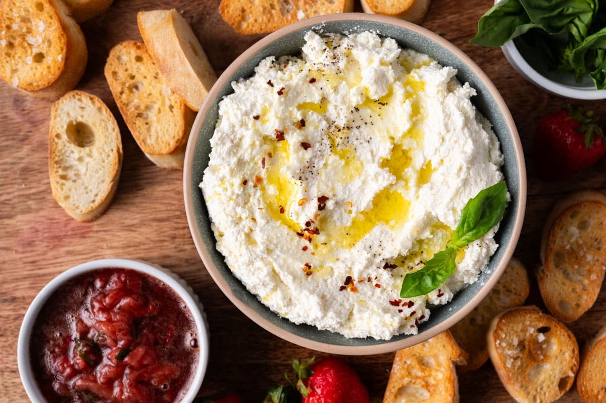whipped feta in a bowl with crostini and strawberry jam