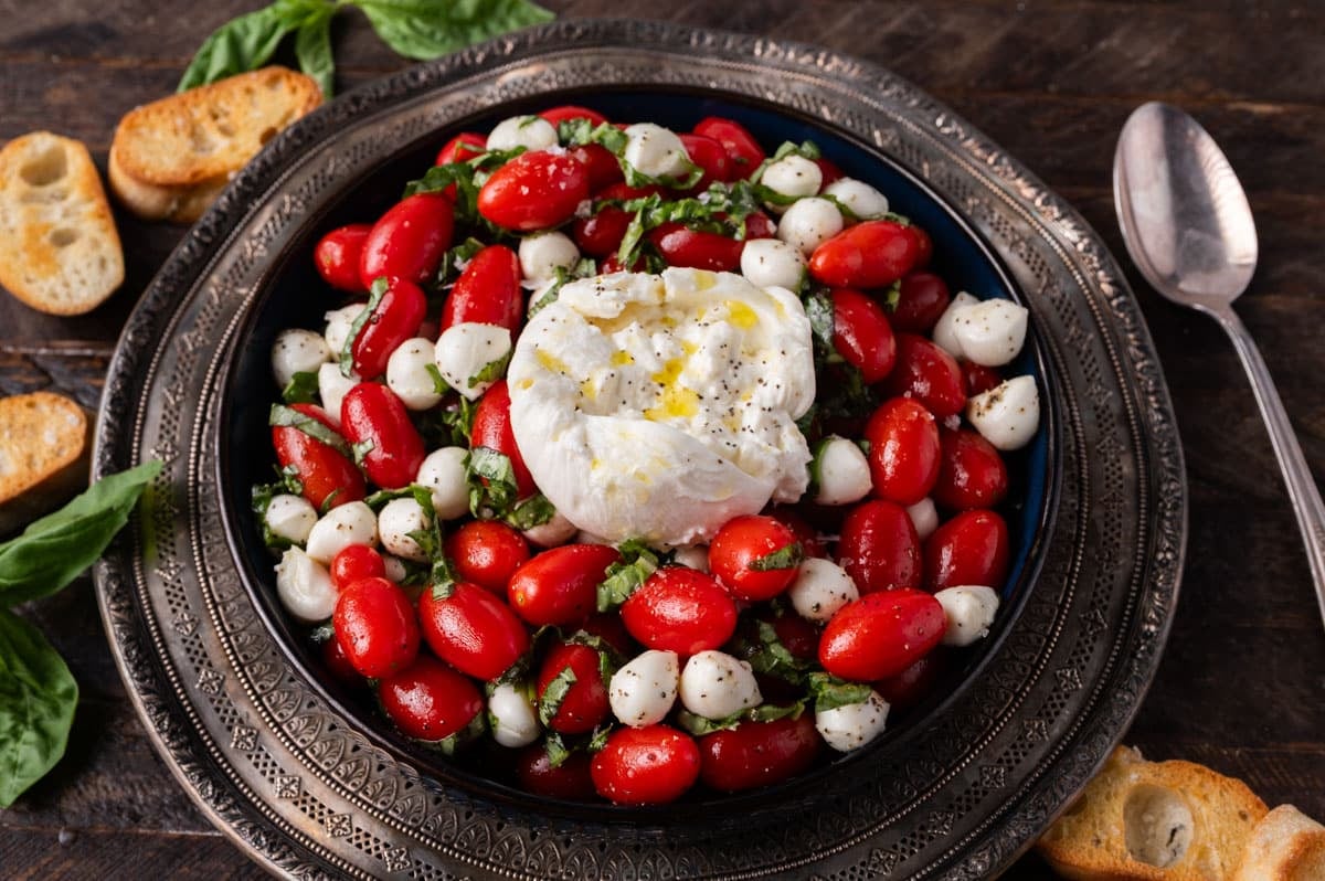 a bowl of caprese salad with burrata on top
