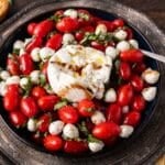 caprese salad in a bowl with burrata on top