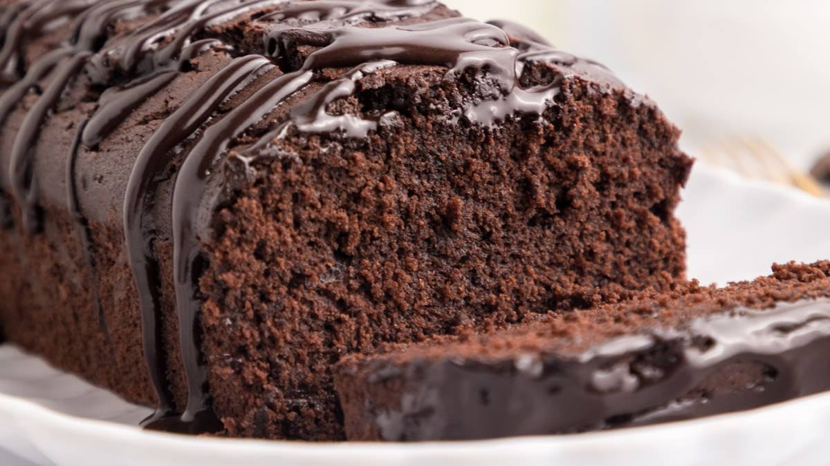 a chocolate olive oil loaf cake on a table with one slice cut