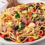 spaghetti salad in a white bowl with a spatula