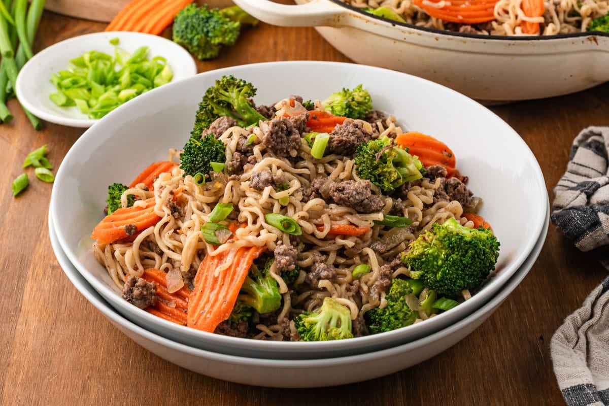 a bowl of ramen noodles with ground beef, broccoli and carrots