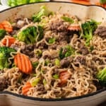 a bowl of ramen noodles with ground beef, broccoli and carrots