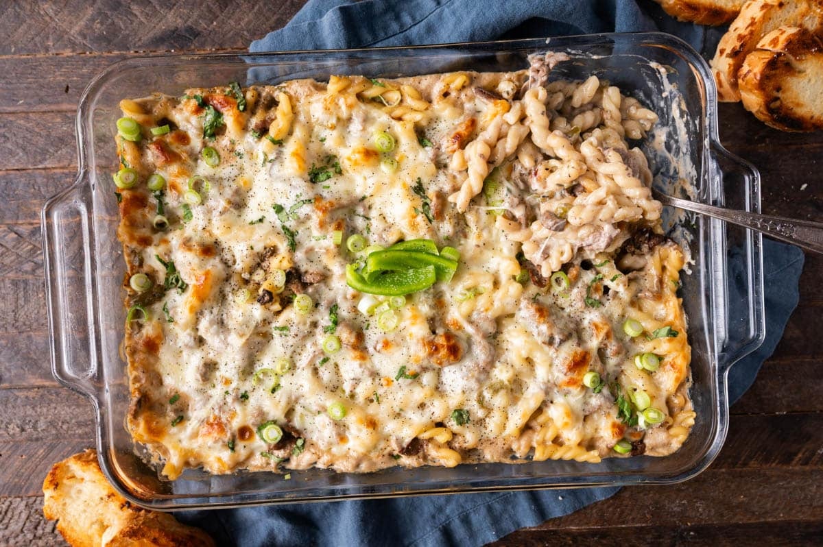 philly cheesesteak casserole on a table with a spoon and bread