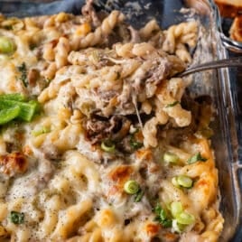 a spoonful of a pasta bake with shaved beef and green peppers on a table