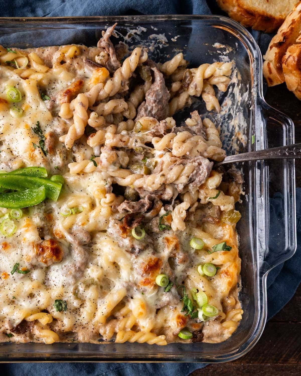 philly cheesesteak bake in a casserole dish with a spoon