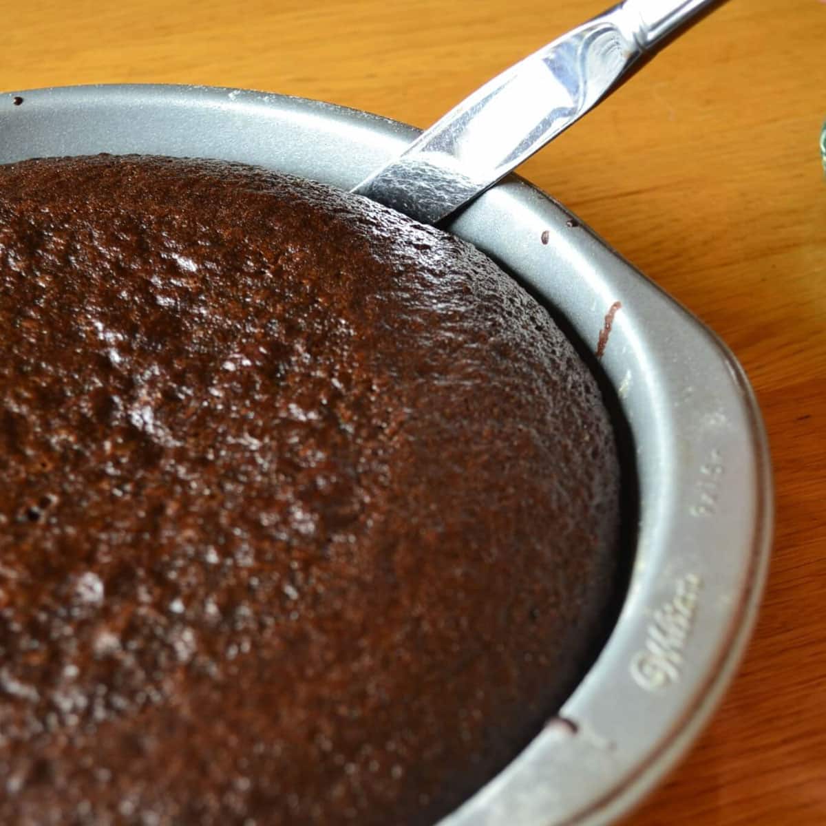 using a knife to loosen a chocolate cake from the sides of the pan