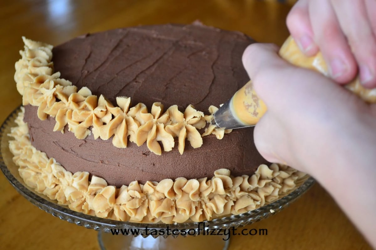 Reese's Peanut Butter Cake piping peanut butter frosting on a reese's cake