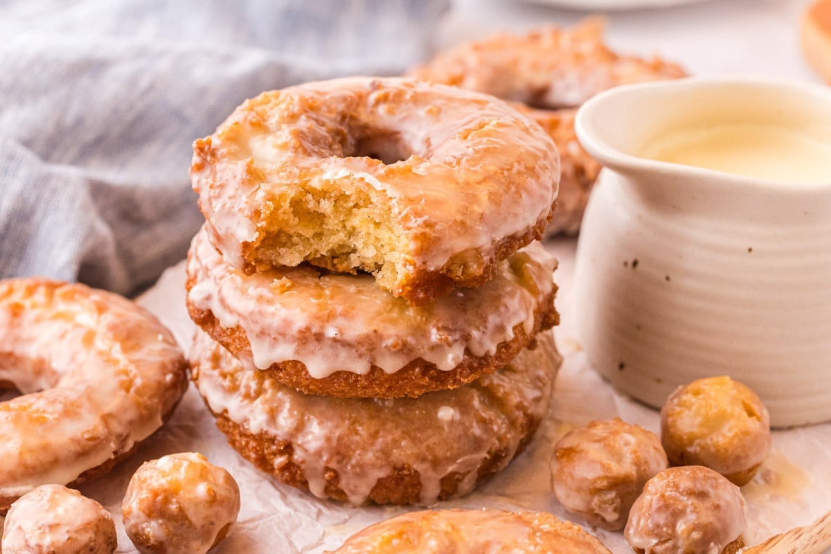a stack of 3 old fashioned donuts, one with a bite out