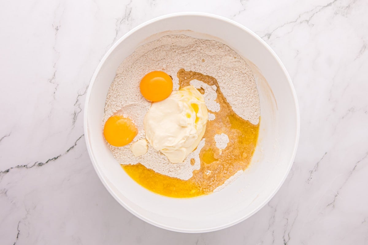 eggs, sour cream and butter in a bowl over dry ingredients