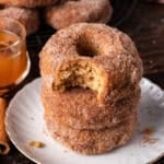 a stack of 3 apple cider donuts with one bite out