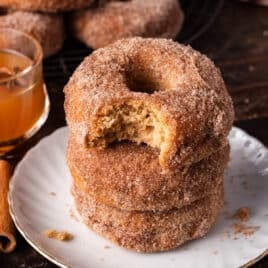 a stack of 3 apple cider donuts with one bite out