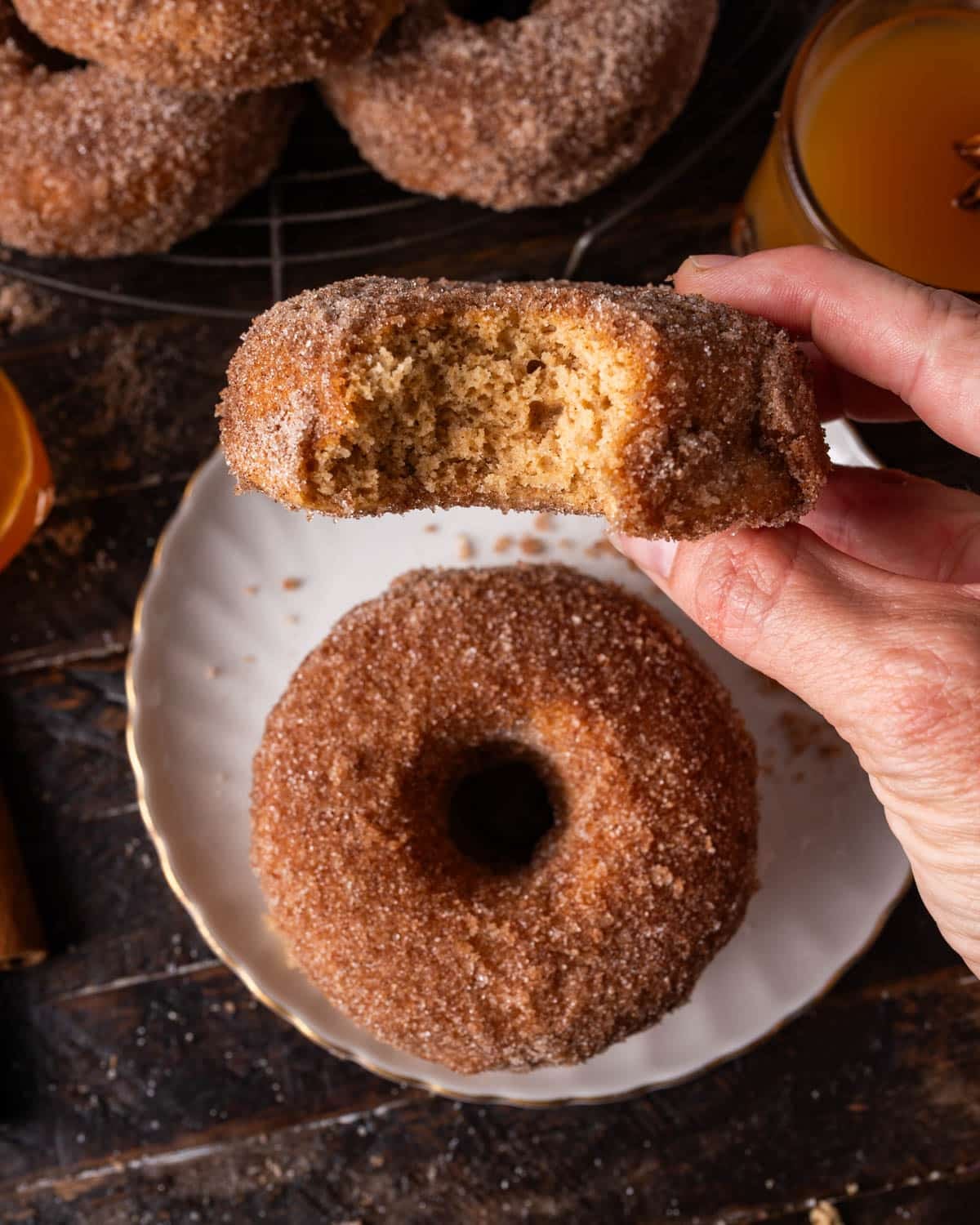 a hand holding a apple donut with a bite out of it