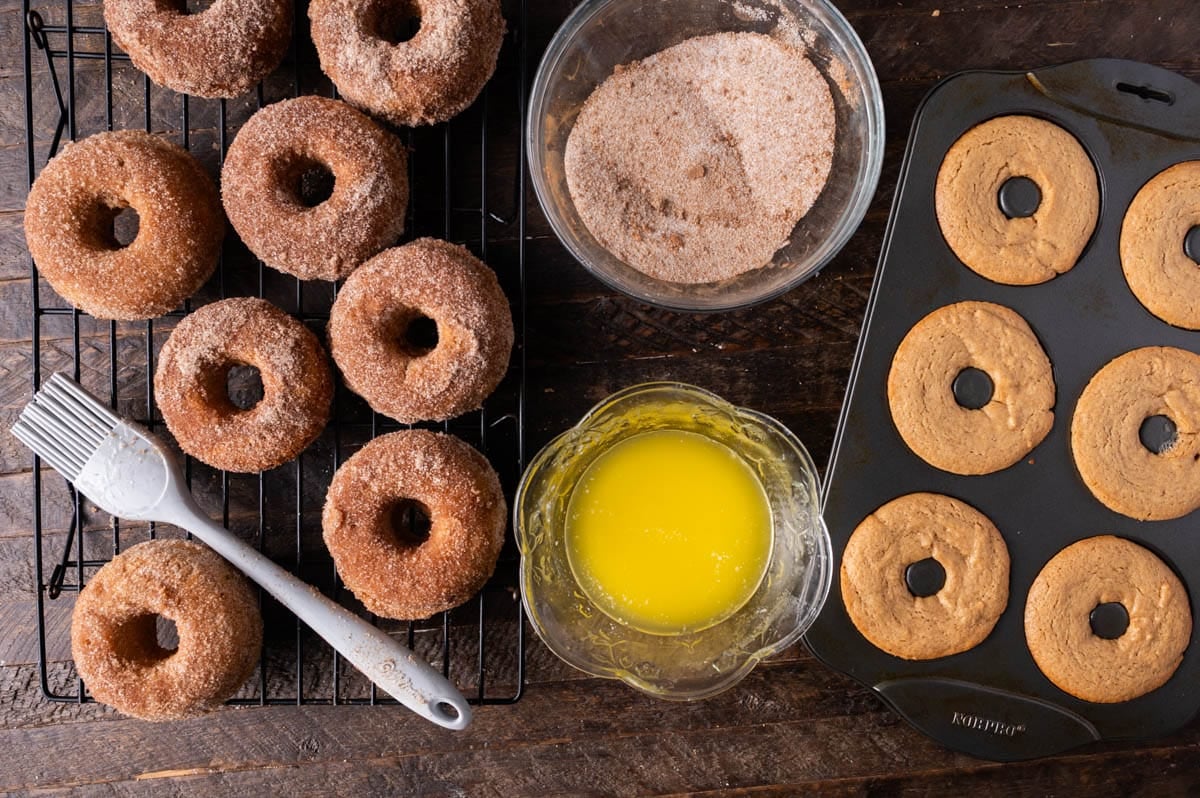 donuts on a pan with bowls of butter, cinnamon sugar and a pastry brush