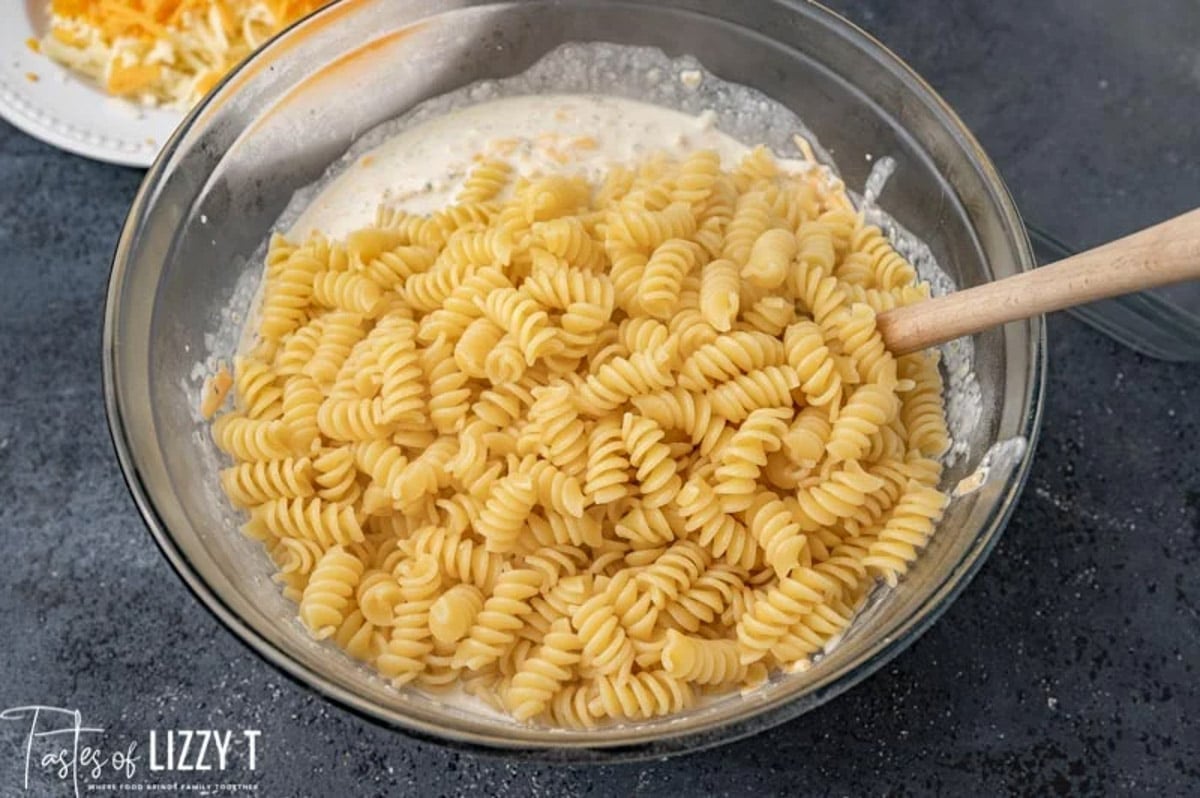 rotini over ranch sauce in a glass bowl with a spoon