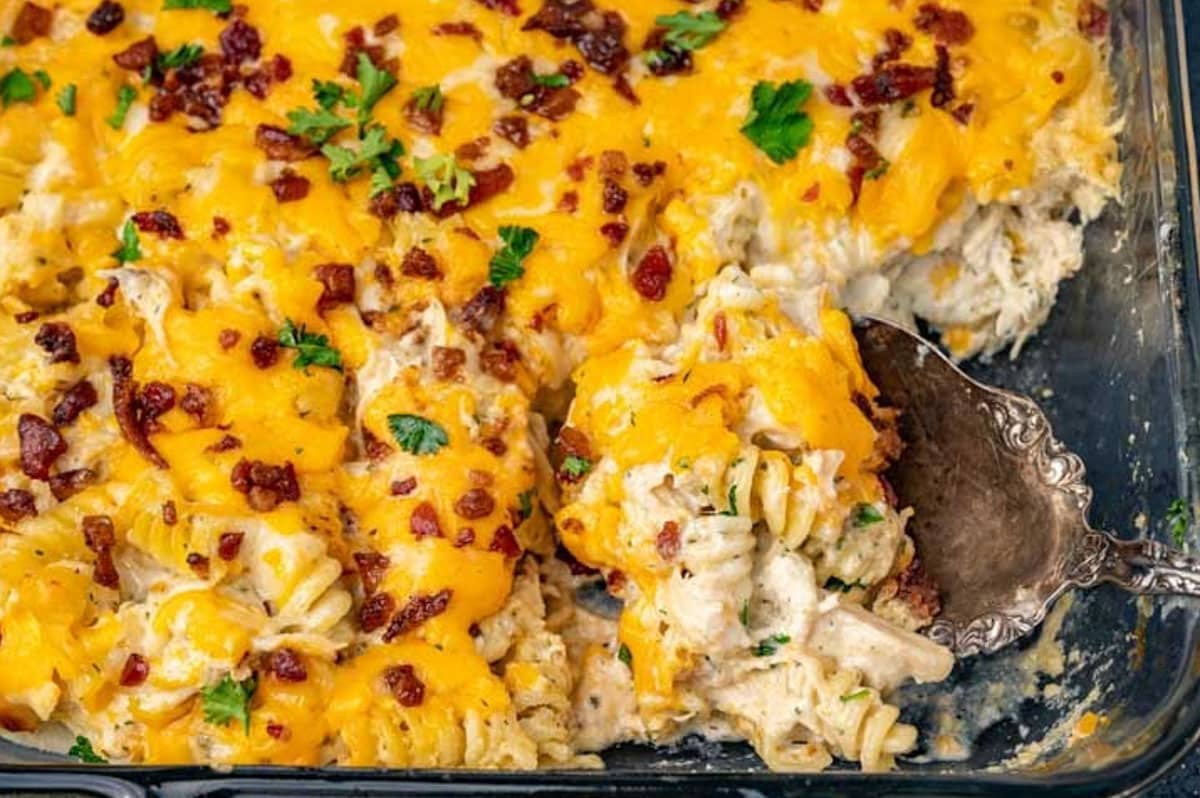 closeup of a spoonful of crack chicken pasta in a glass 9x13 dish