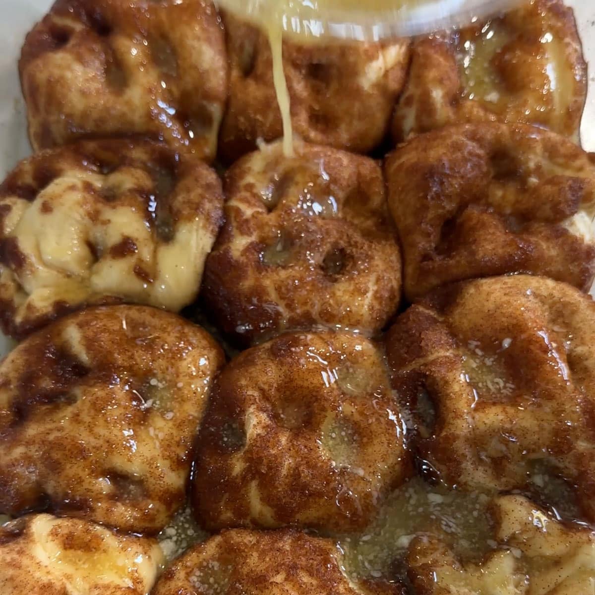 butter pouring over unbaked rolls