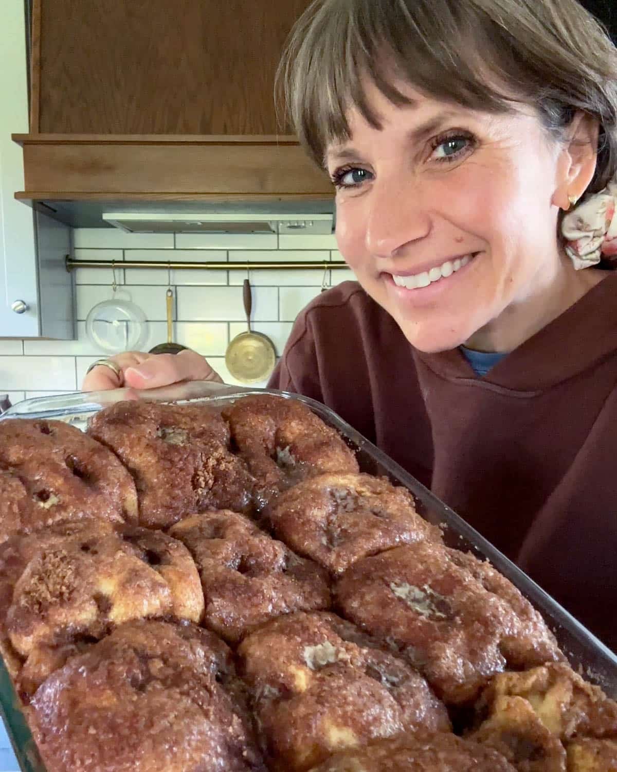 julie holding a pan of baked no roll cinnamon rolls
